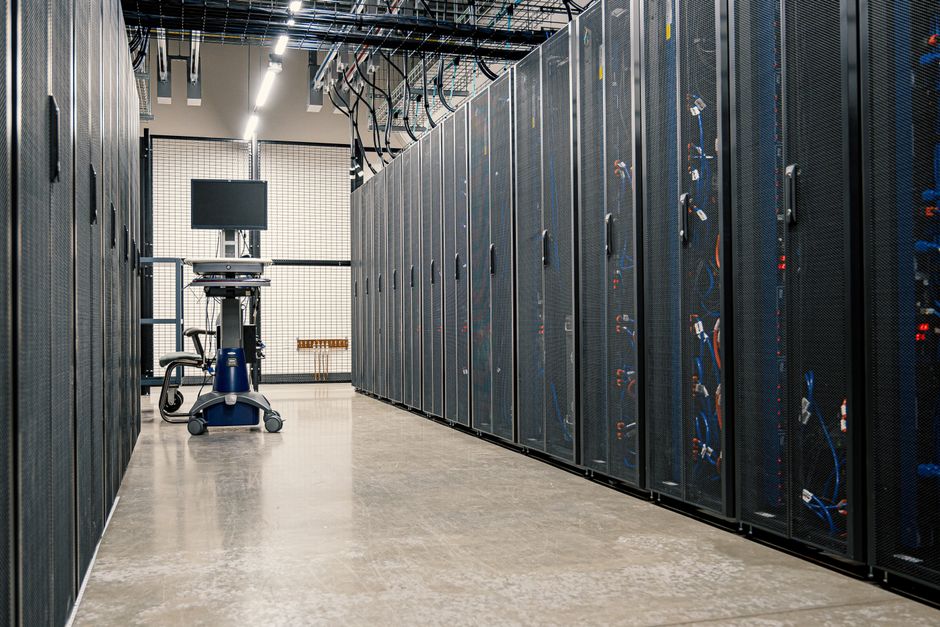 Armarios de estructura de acero que albergan servidores, dispositivos de red y cables en un centro de datos moderno y equipado.